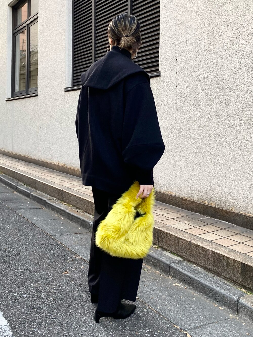ブラック系のその他アウター、ブラック系のニット/セーター、イエロー系のハンドバッグを着用したレディースの秋コーディネートの2枚目の写真