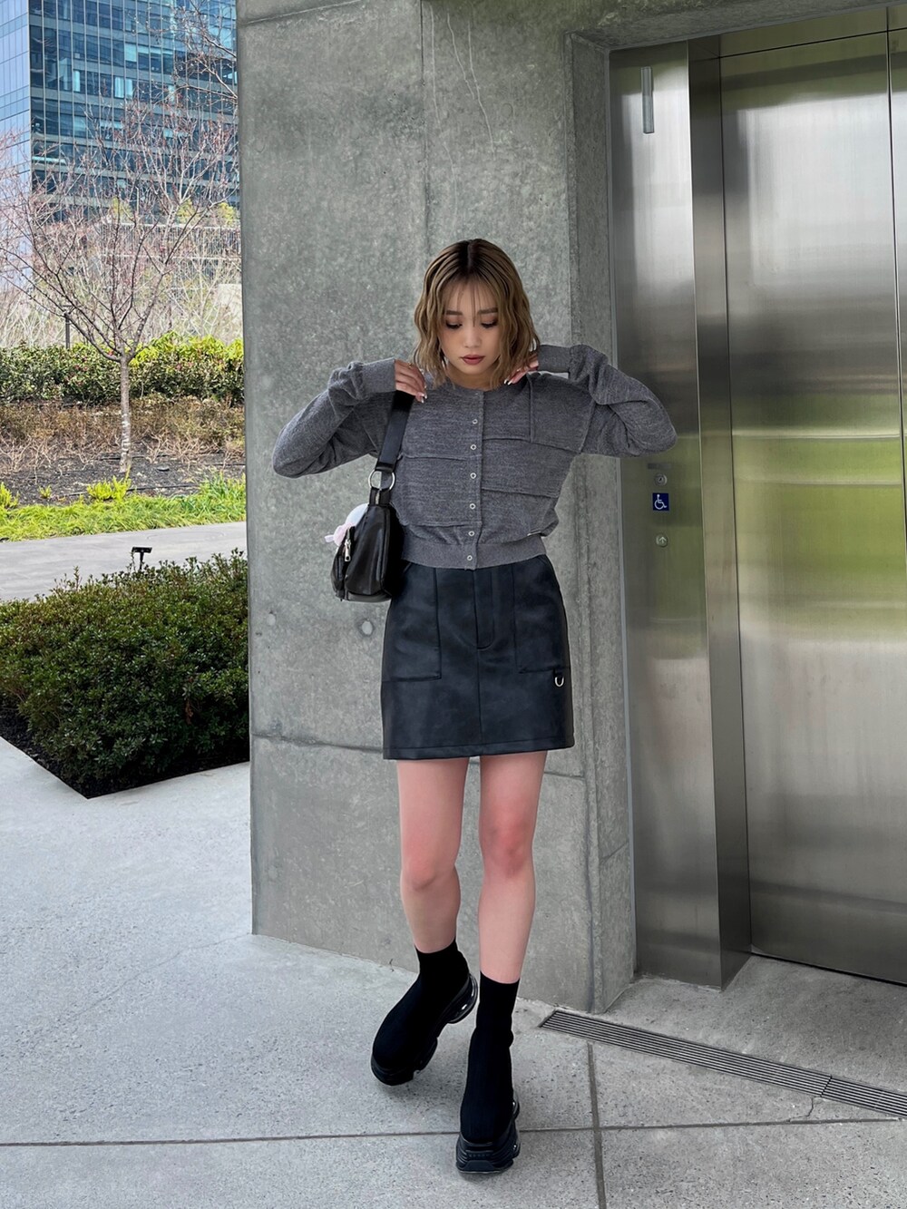 ブラック系のブーツ、ブラック系のスカート、グレー系のカーディガン/ボレロを着用したレディースの春コーディネートの3枚目の写真