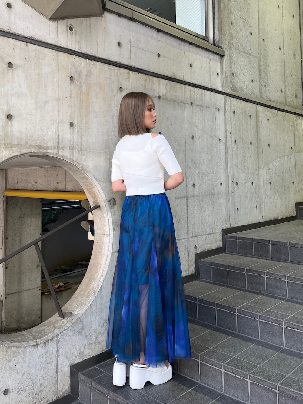 ホワイト系のニット/セーター、ブルー系のスカート、ホワイト系のサンダルを着用したレディースの冬コーディネートの3枚目の写真