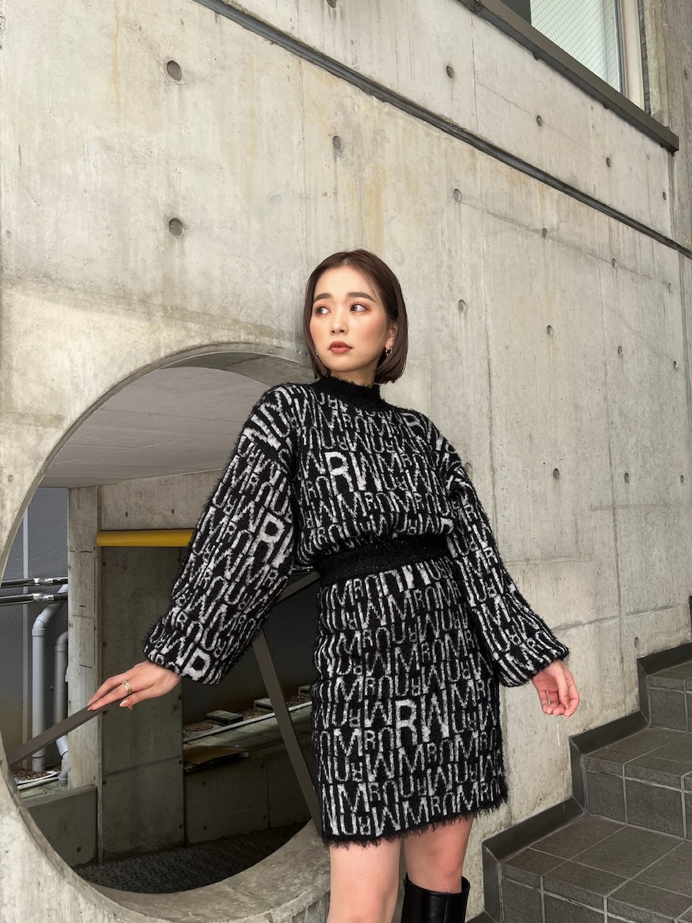 グレー系のダウンベスト、ブラック系のニット/セーター、ブラック系のスカートを着用したレディースの秋コーディネートの7枚目の写真