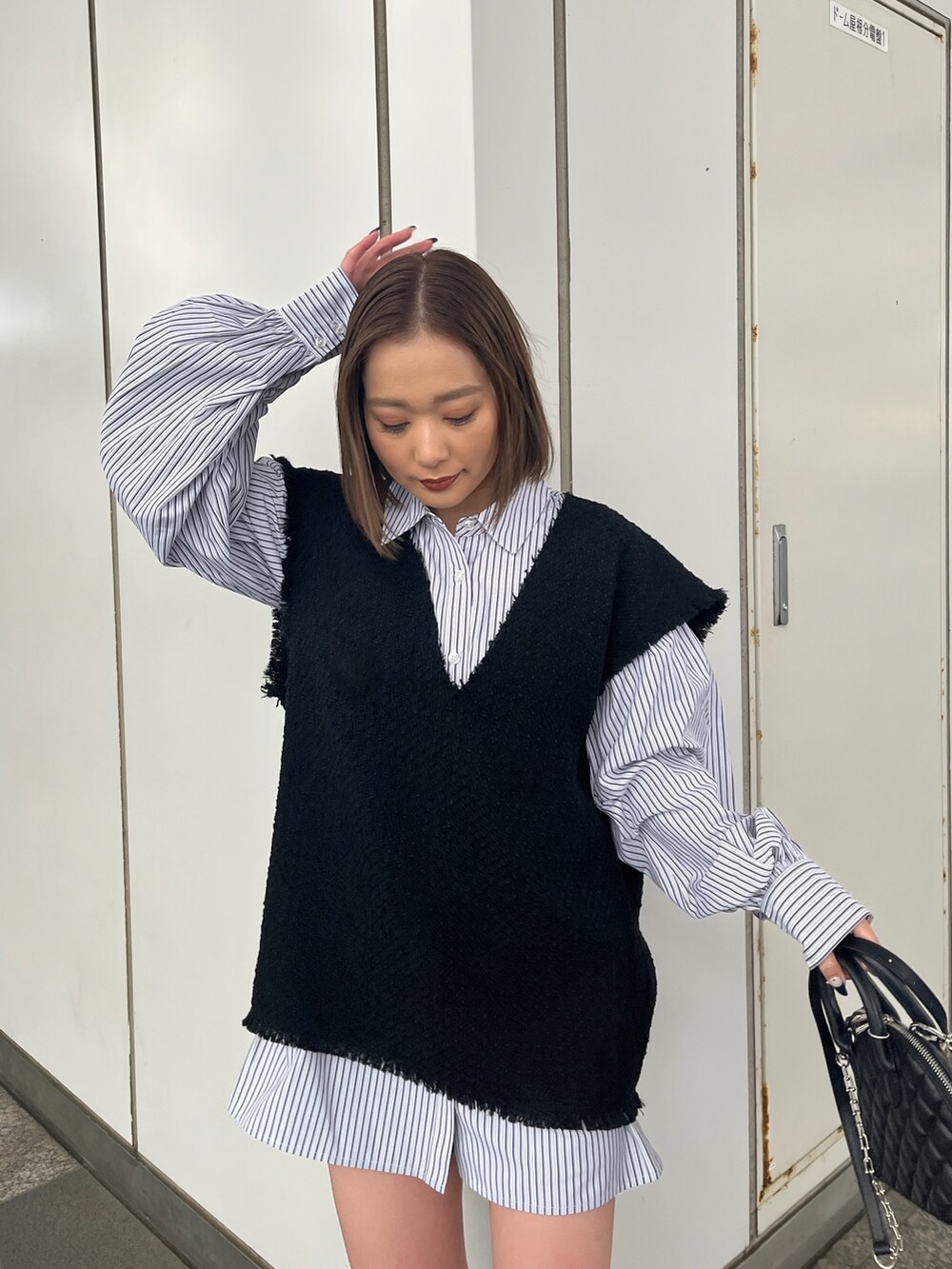 ブラック系のワンピース、ブラック系のハンドバッグ、ブラック系のブーツを着用したレディースの冬コーディネートの3枚目の写真