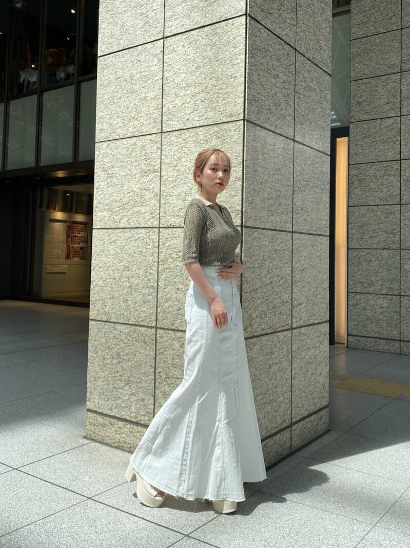 ホワイト系のキャミソール、ブラウン系のポロシャツ、ホワイト系のデニムスカートを着用したレディースの春コーディネートの3枚目の写真