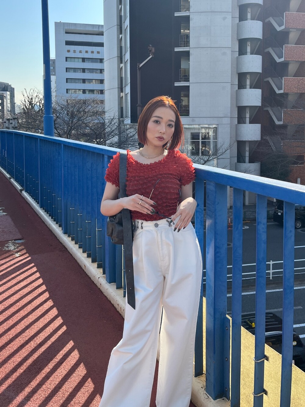 ホワイト系のデニムパンツ、ブラック系のショルダーバッグ、レッド系のシャツ/ブラウスを着用したレディースの春コーディネートの5枚目の写真