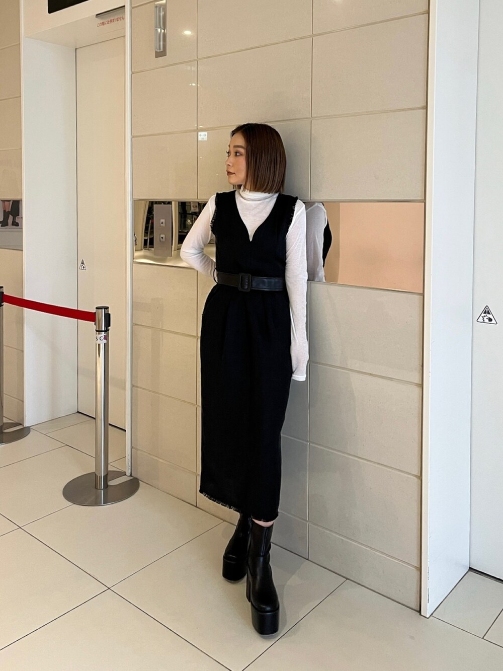 ホワイト系のTシャツ/カットソー、ブラック系のワンピース、ブラック系のブーツを着用したレディースの冬コーディネートの2枚目の写真