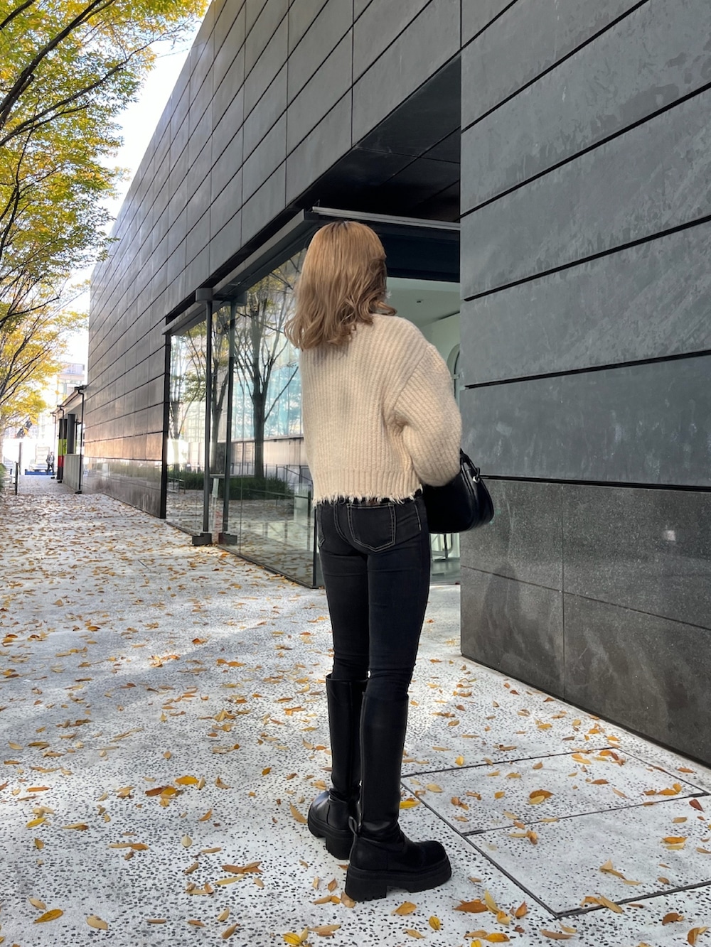 ホワイト系のニット/セーター、ブラック系のハンドバッグ、ブラック系のブーツを着用したレディースの秋コーディネートの5枚目の写真