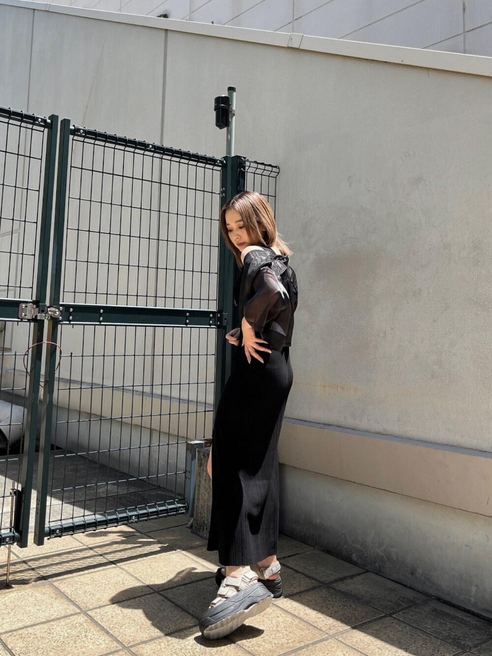 ブラック系のシャツ/ブラウス、ブラック系のワンピース、ブラウン系のサンダルを着用したレディースの春コーディネートの3枚目の写真