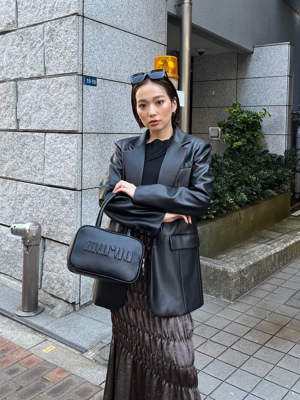 ブラック系のテーラードジャケット、ブラック系のニット/セーター、ブラウン系のスカートを着用したレディースの春コーディネートの6枚目の写真