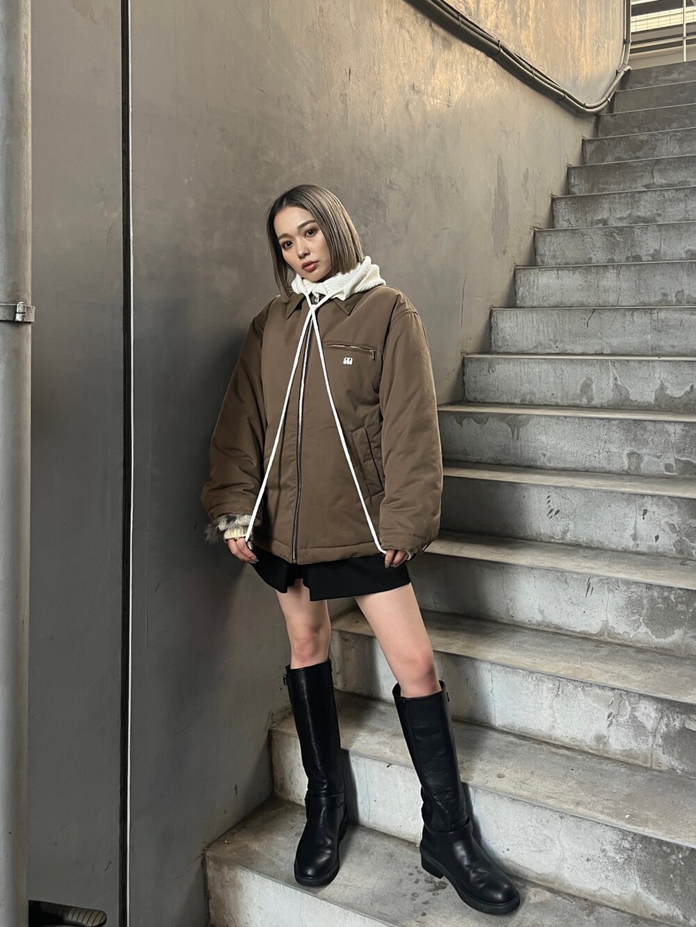 ブラウン系のブルゾン、ブラック系のブーツを着用したレディースの秋コーディネートの3枚目の写真