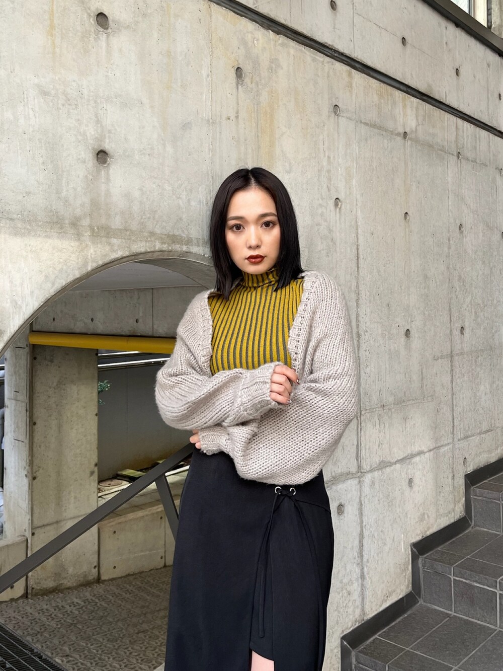 ベージュ系のトレンチコート、イエロー系のニット/セーター、ブラック系のスカートを着用したレディースの夏コーディネートの9枚目の写真