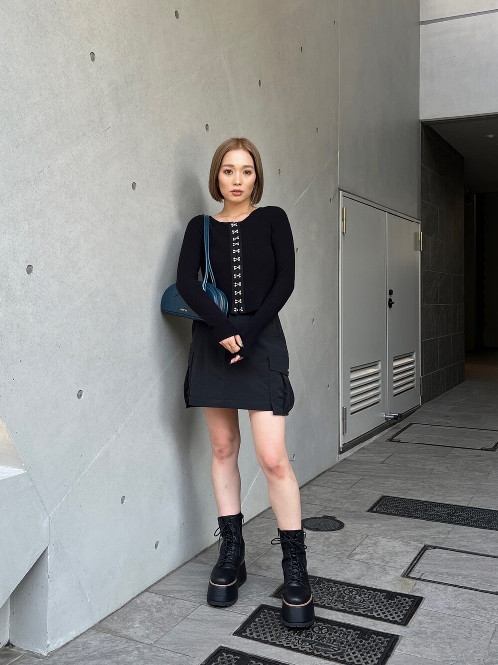 ブラック系のブーツ、ブラック系のスカート、ブラック系のニット/セーターを着用したレディースの夏コーディネートの2枚目の写真