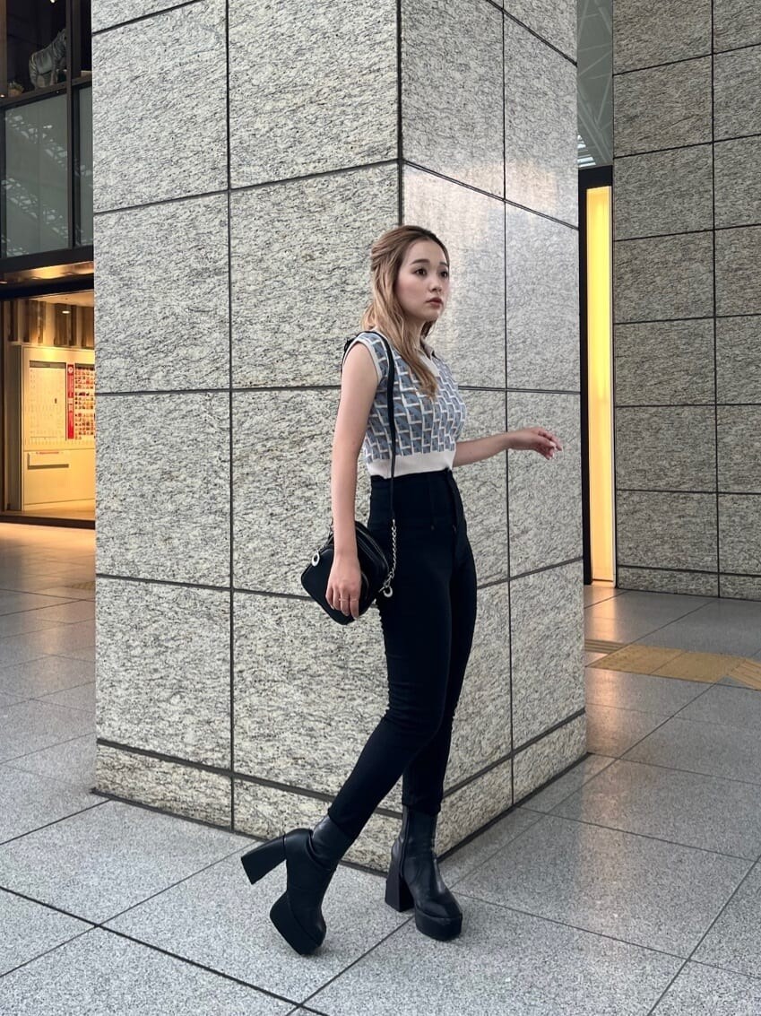 ブラック系のデニムパンツ、ブラック系のショルダーバッグ、ホワイト系のニット/セーターを着用したレディースの夏コーディネートの2枚目の写真