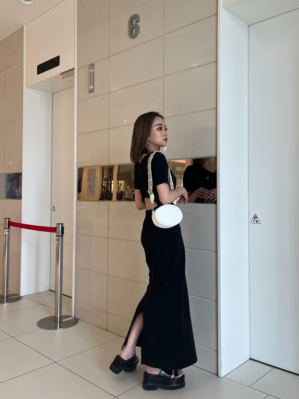 ブラック系のワンピース、ホワイト系のショルダーバッグ、ブラック系のサンダルを着用したレディースの夏コーディネートの3枚目の写真