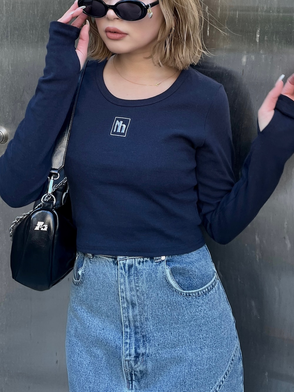 ブルー系のTシャツ/カットソー、ブルー系のデニムスカート、ブラック系のショルダーバッグを着用したレディースの春コーディネートの6枚目の写真