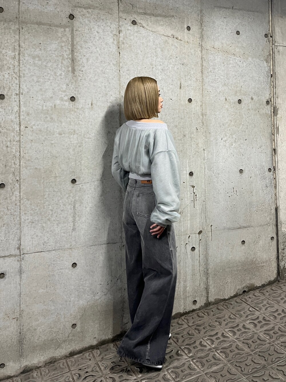 グレー系のスウェット、ブラック系のデニムパンツ、シルバー系のパンプスを着用したレディースの冬コーディネートの3枚目の写真