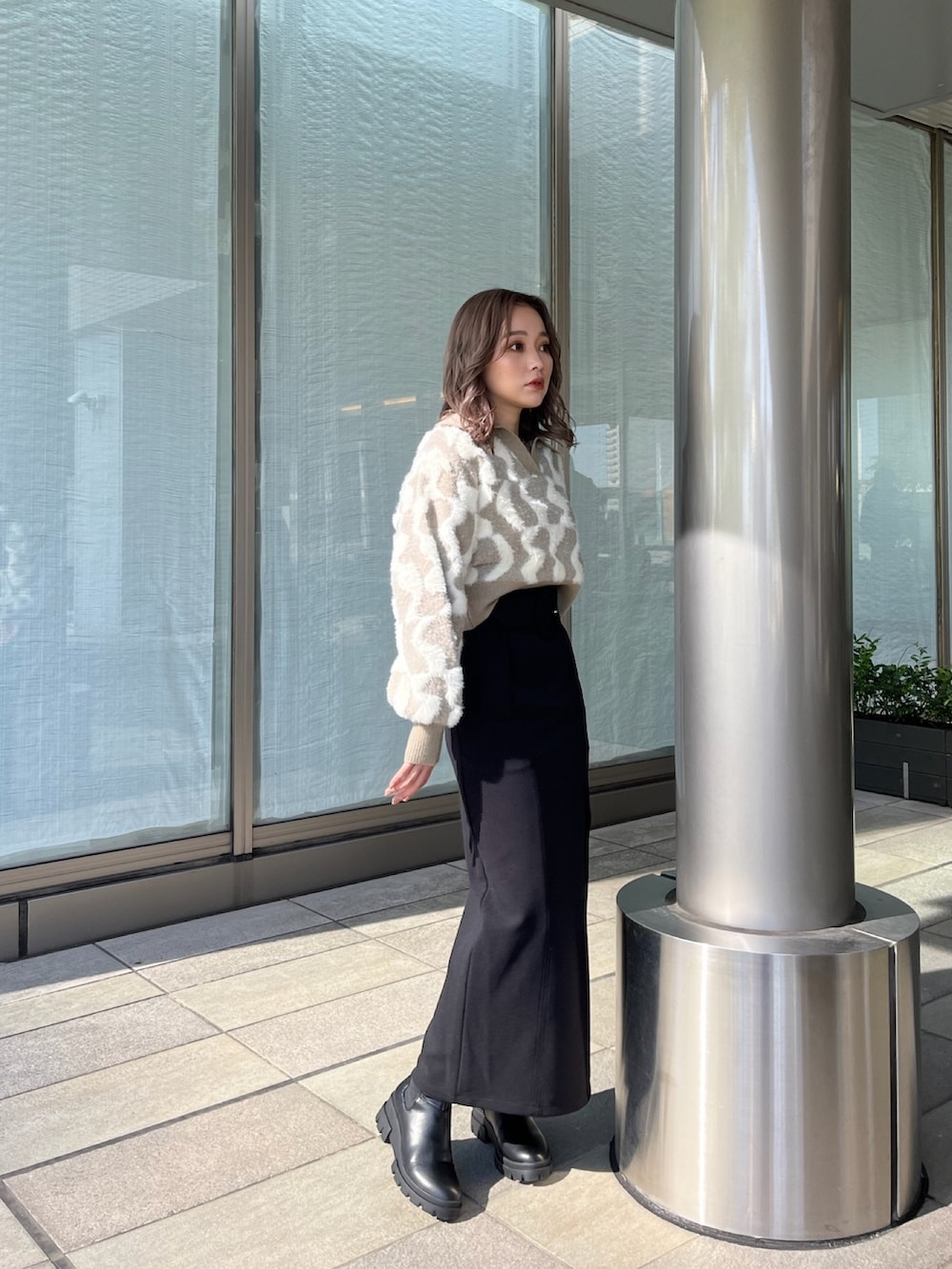 ベージュ系のニット/セーター、ブラック系のスカート、ブラック系のブーツを着用したレディースの秋コーディネートの2枚目の写真