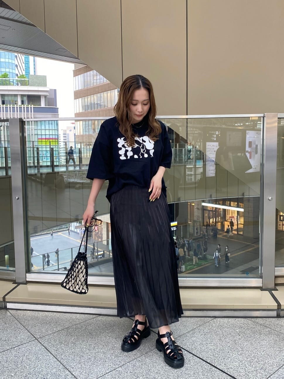 ブラック系のスカート、ブラック系のハンドバッグ、ブラック系のTシャツ/カットソーを着用したレディースの春コーディネートの2枚目の写真