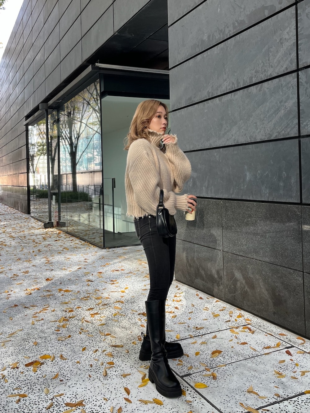 ホワイト系のニット/セーター、ブラック系のハンドバッグ、ブラック系のブーツを着用したレディースの秋コーディネートの4枚目の写真