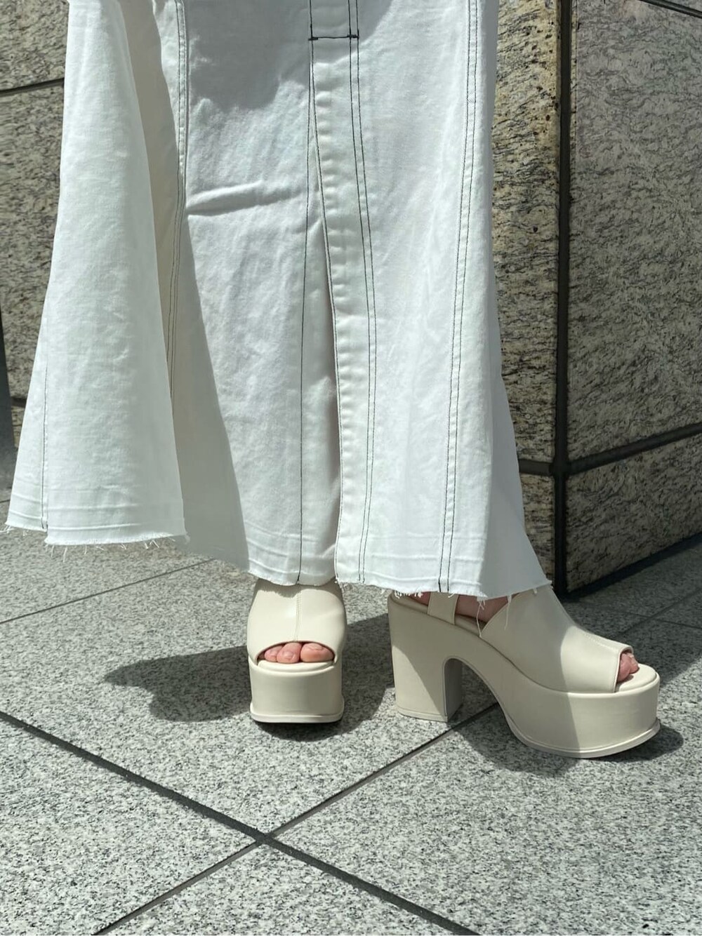 ホワイト系のキャミソール、ブラウン系のポロシャツ、ホワイト系のデニムスカートを着用したレディースの春コーディネートの8枚目の写真