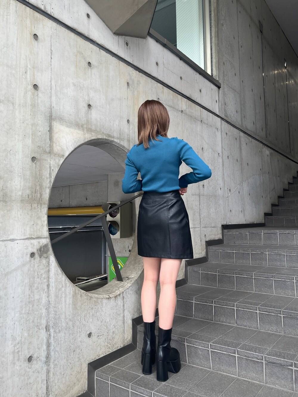 ホワイト系のブルゾン、ブルー系のニット/セーター、ブラック系のブーツを着用したレディースの秋コーディネートの6枚目の写真