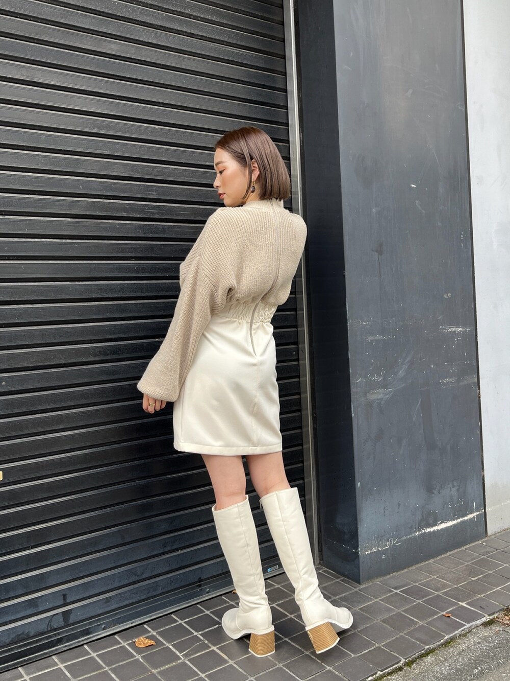 ベージュ系のワンピース、ホワイト系のブーツを着用したレディースの秋コーディネートの2枚目の写真