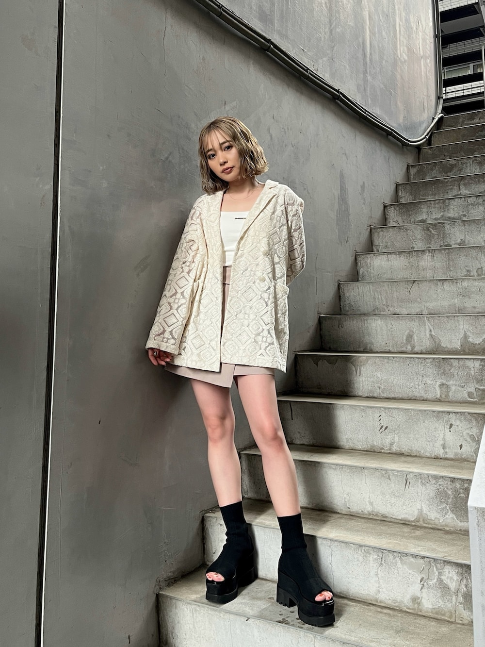 ホワイト系のテーラードジャケット、ホワイト系のキャミソール、ベージュ系のスカートを着用したレディースの春コーディネートの2枚目の写真