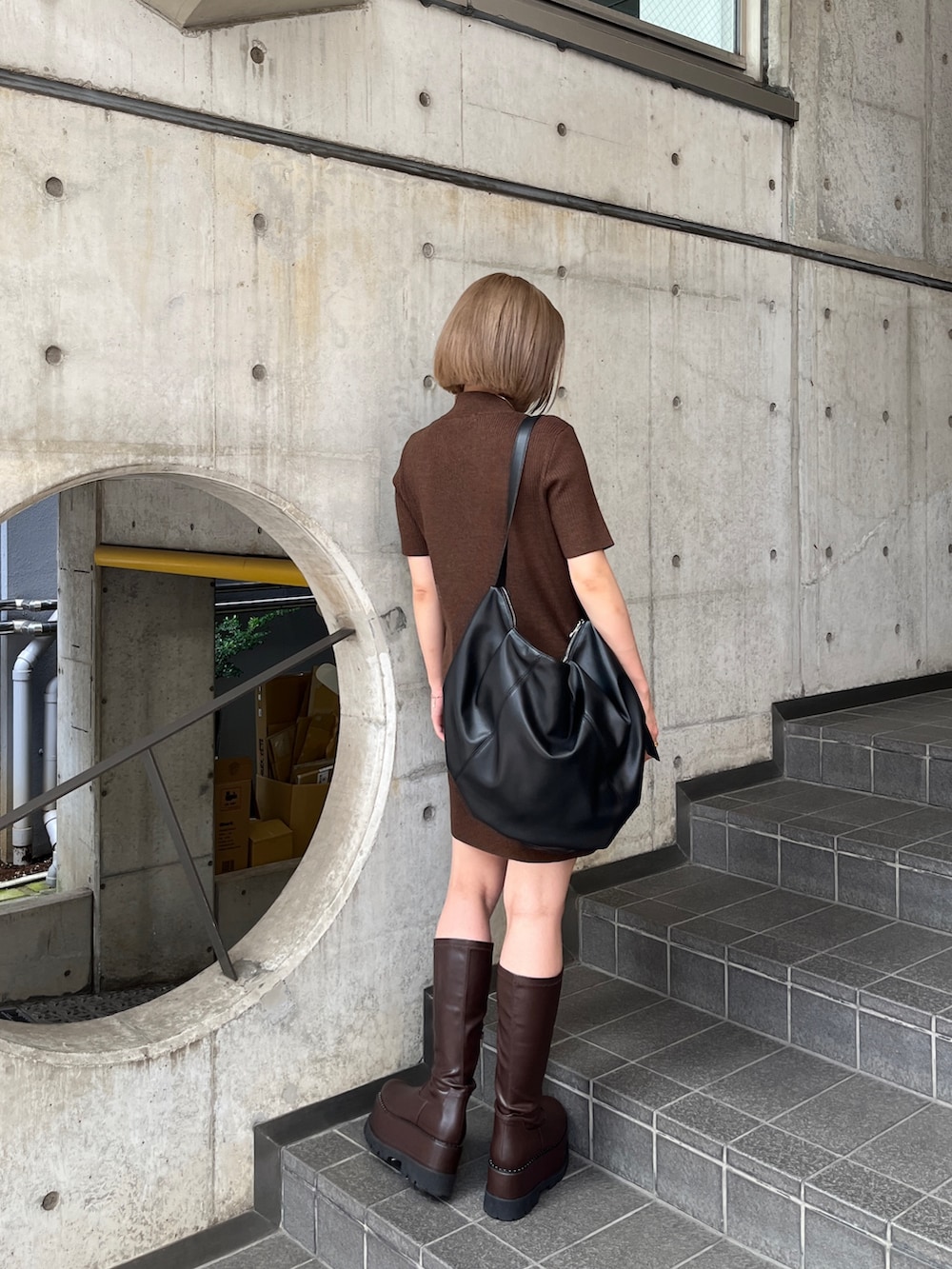 ブラウン系のワンピース、ブラウン系のブーツ、ブラック系のハンドバッグを着用したレディースの夏コーディネートの3枚目の写真