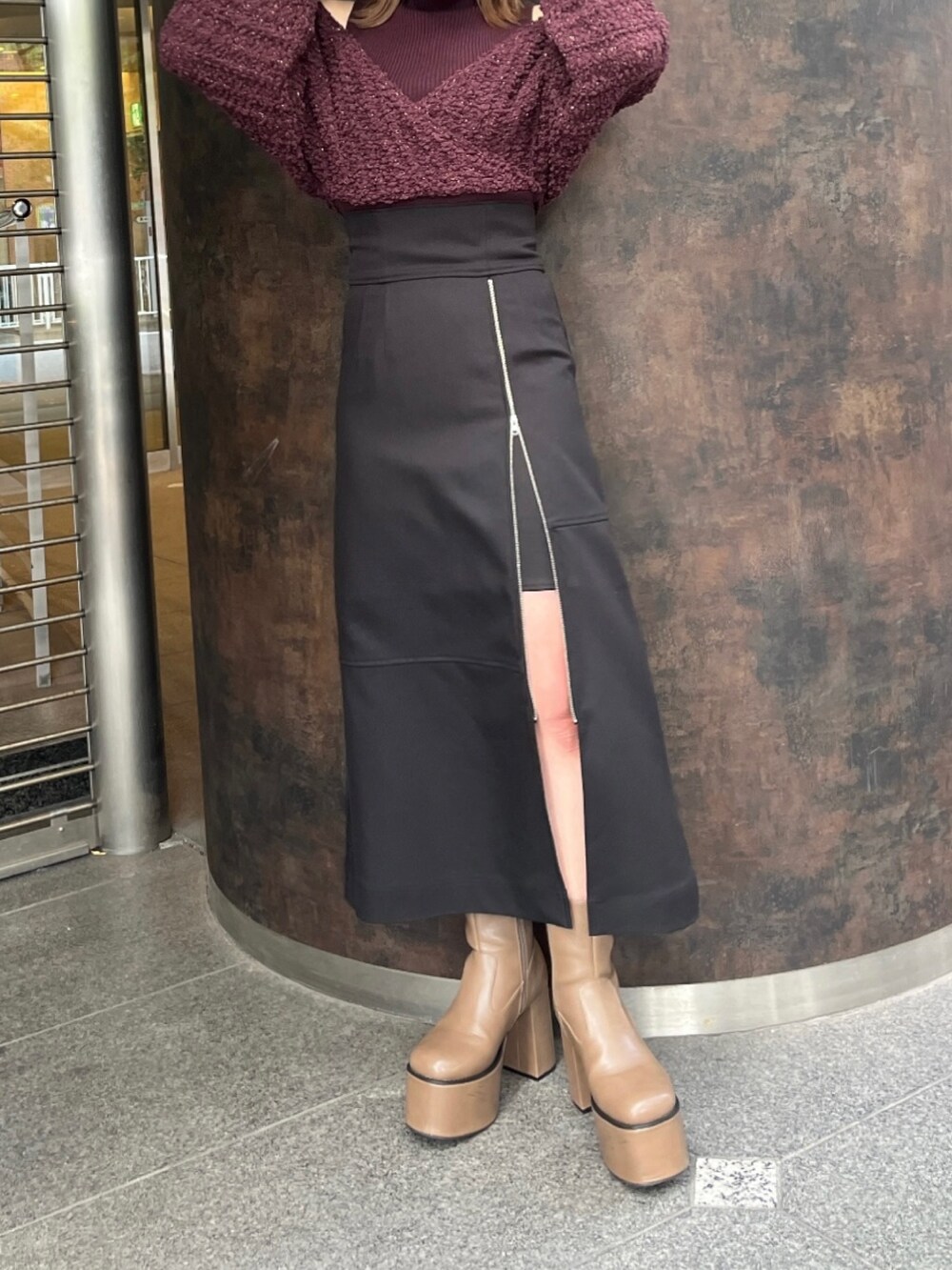 ブラック系のスカート、レッド系のニット/セーター、ブラウン系のブーツを着用したレディースの秋コーディネートの4枚目の写真