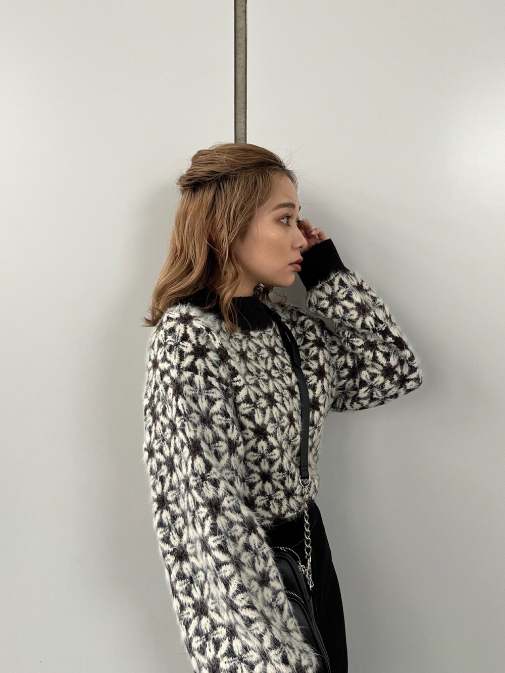 ブラック系のニット/セーター、ブラック系のスカート、ブラック系のショルダーバッグを着用したレディースの秋コーディネートの5枚目の写真