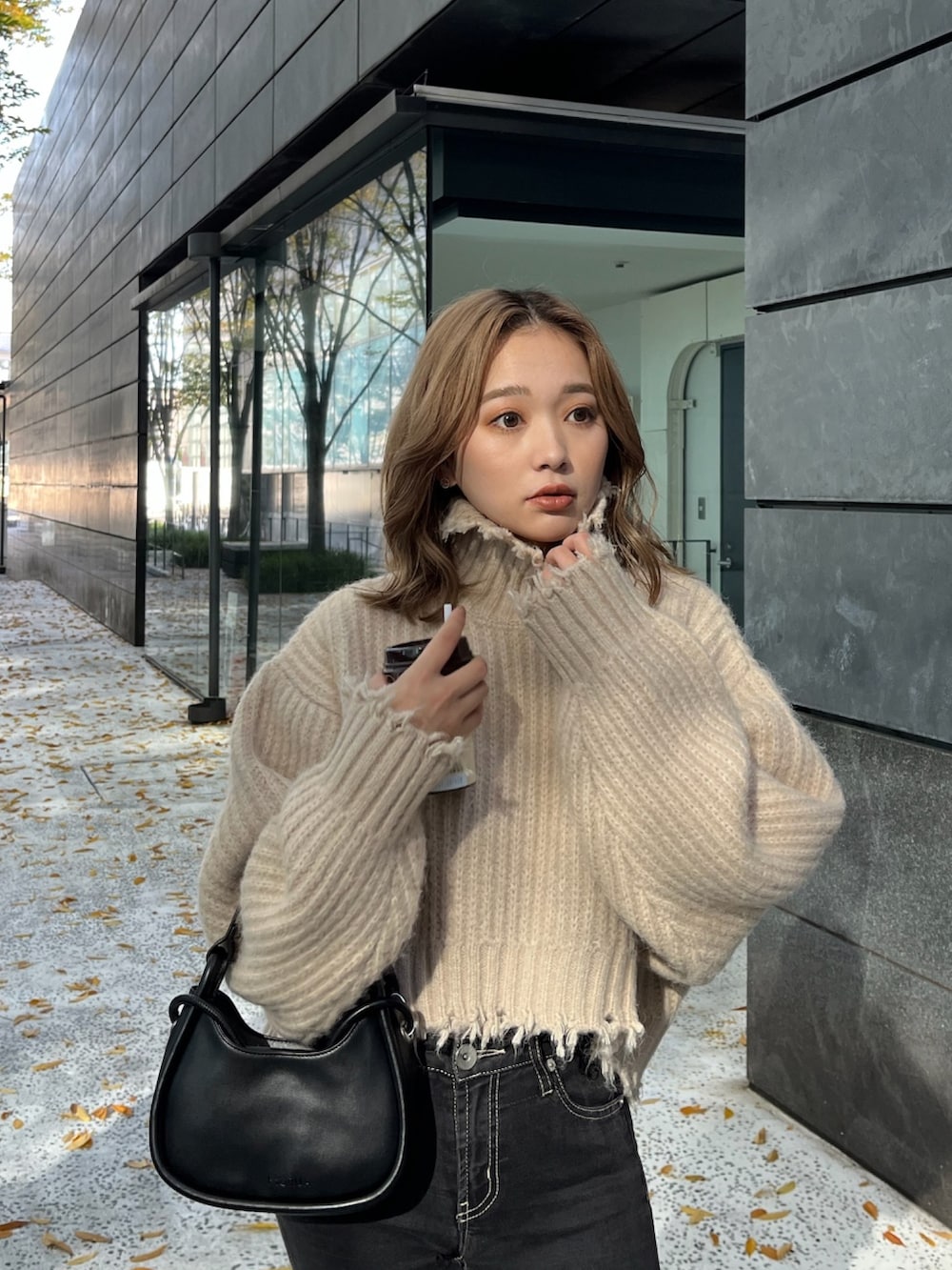 ホワイト系のニット/セーター、ブラック系のハンドバッグ、ブラック系のブーツを着用したレディースの秋コーディネートの6枚目の写真