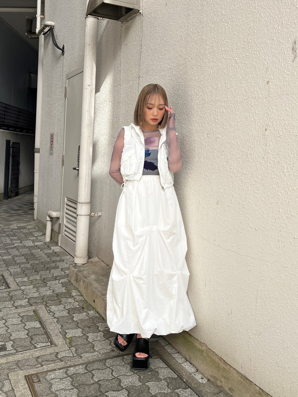 グレー系のTシャツ/カットソー、ホワイト系のベスト、ホワイト系のスカートを着用したレディースの冬コーディネートの3枚目の写真