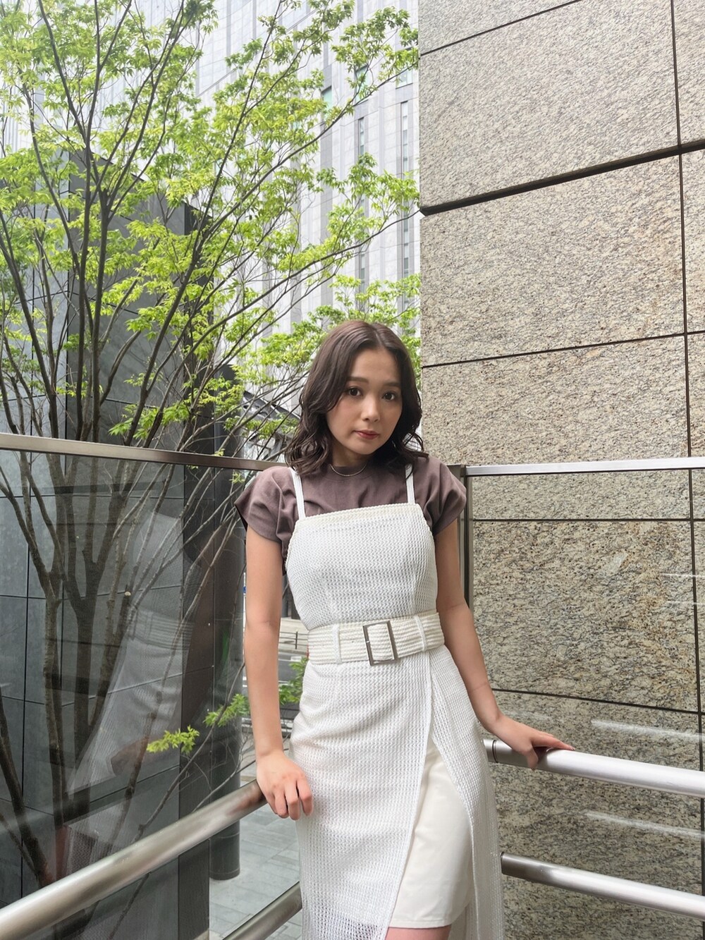 ホワイト系のワンピース、ブラウン系のTシャツ/カットソー、ブラック系のサンダルを着用したレディースの春コーディネートの3枚目の写真