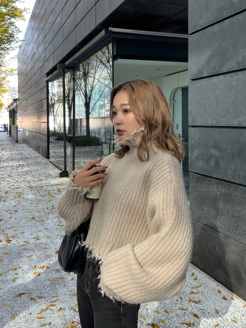 ホワイト系のニット/セーター、ブラック系のハンドバッグ、ブラック系のブーツを着用したレディースの秋コーディネートの7枚目の写真