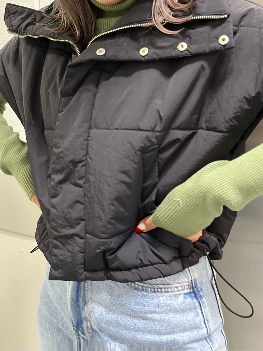 ブラック系のダウンベスト、グリーン系のニット/セーター、ブラック系のハットを着用したレディースの秋コーディネートの6枚目の写真