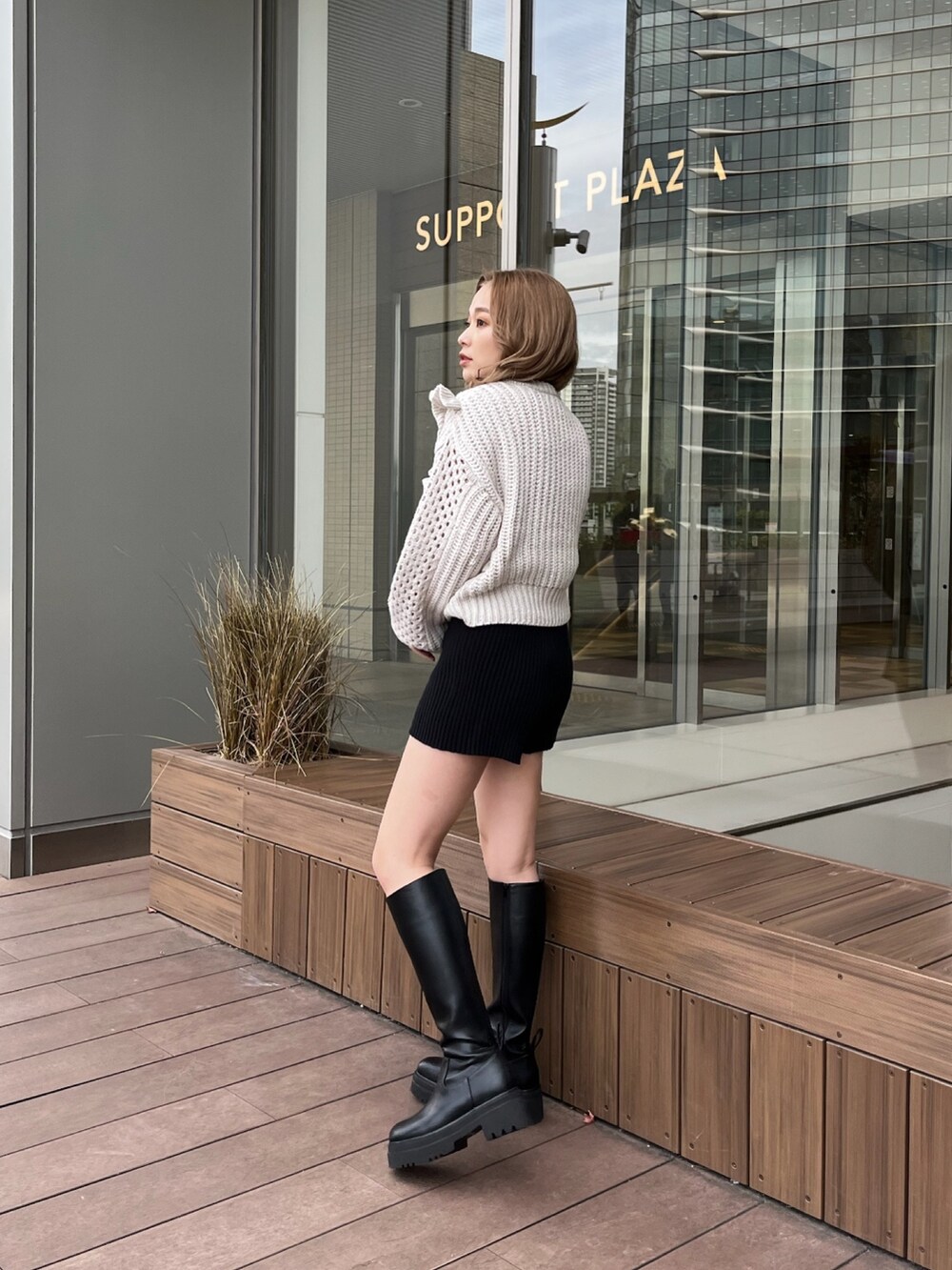 グレー系のニット/セーター、ブラック系のスウェットパンツ、ブラック系のブーツを着用したレディースの冬コーディネートの3枚目の写真