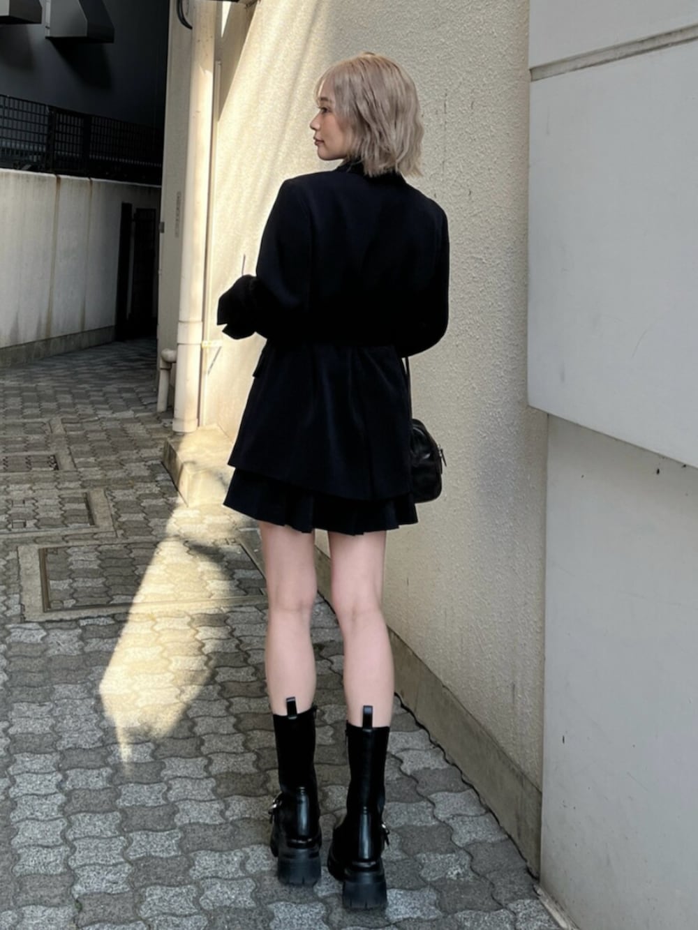 ブラック系のブーツ、ブラック系のテーラードジャケット、ブラウン系のキャミソールを着用したレディースの春コーディネートの4枚目の写真