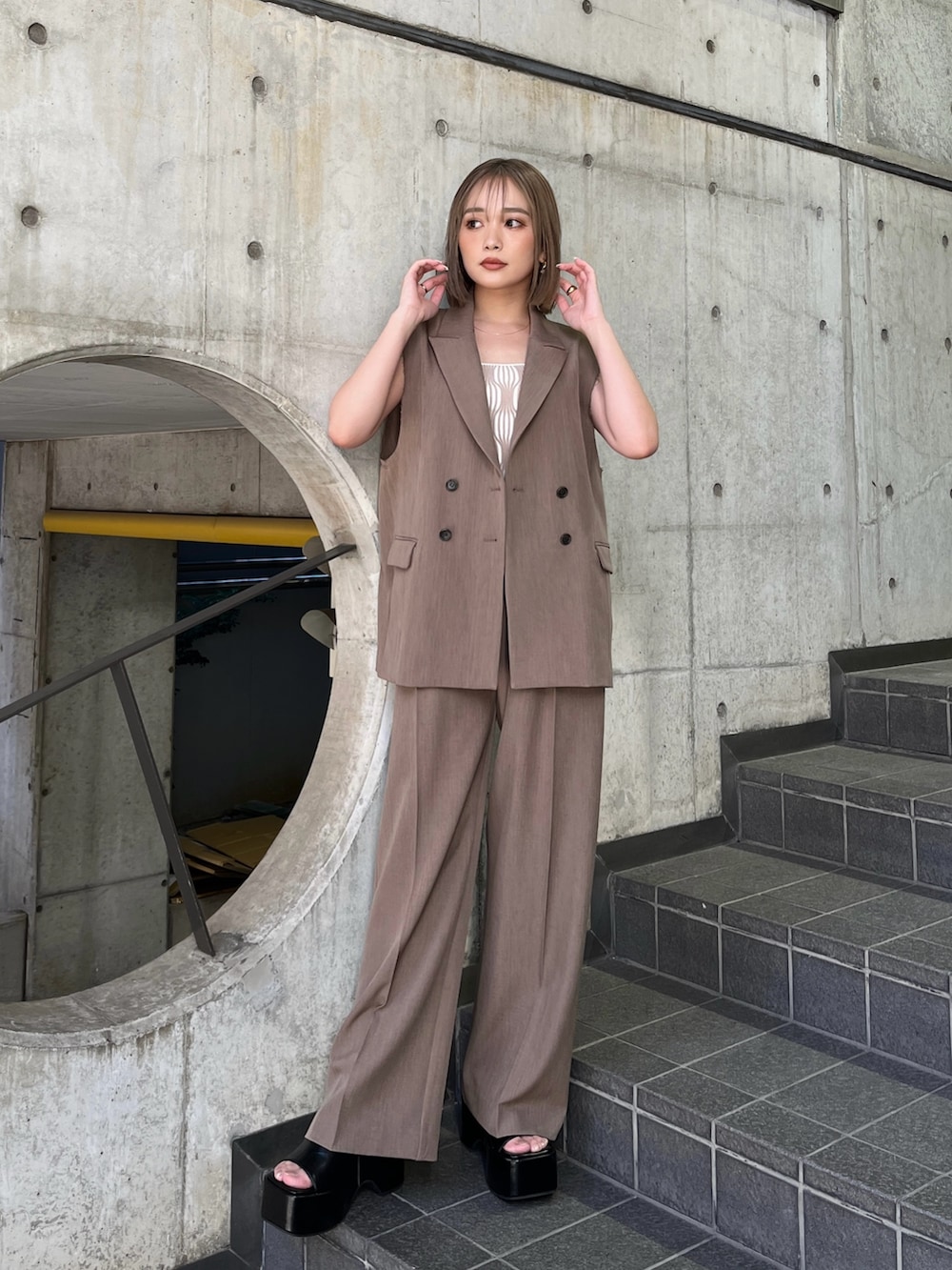 ブラウン系のベスト、ホワイト系のタンクトップ、ブラウン系のその他パンツを着用したレディースの夏コーディネートの2枚目の写真