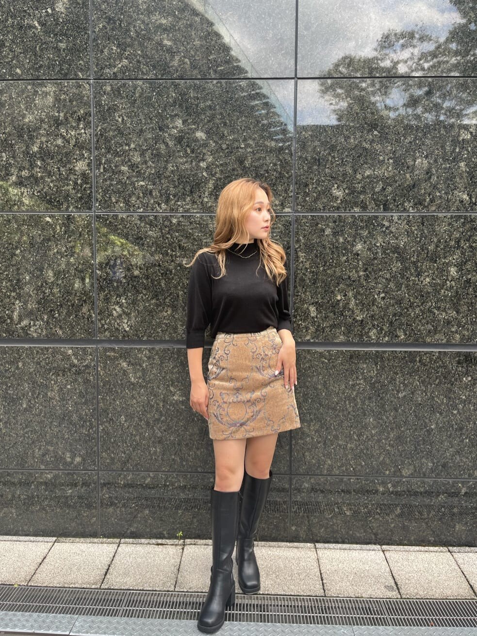 ブラック系のブーツ、ブラック系のニット/セーター、ブラウン系のスカートを着用したレディースの秋コーディネートの2枚目の写真