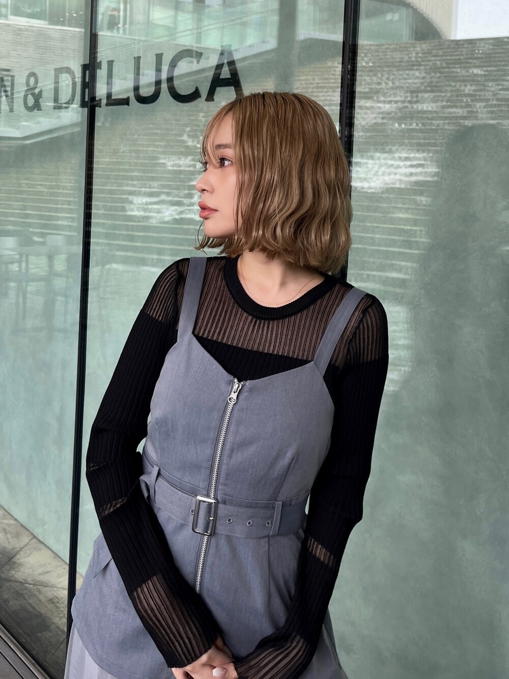 ブラック系のニット/セーター、グレー系のジャンパースカート、ブラック系のブーツを着用したレディースの春コーディネートの4枚目の写真