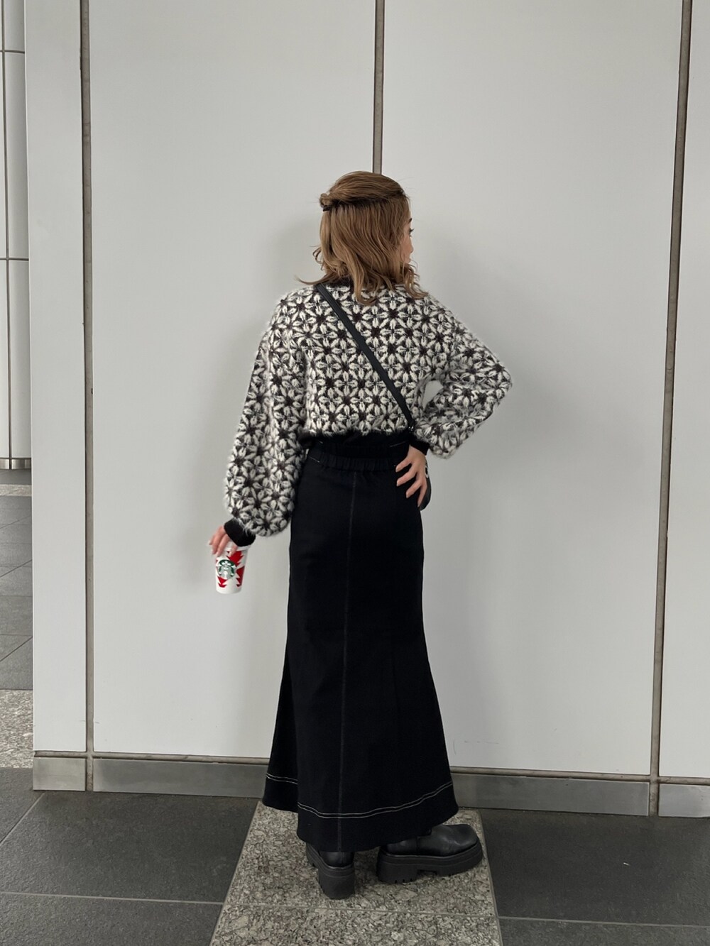 ブラック系のニット/セーター、ブラック系のスカート、ブラック系のショルダーバッグを着用したレディースの秋コーディネートの3枚目の写真