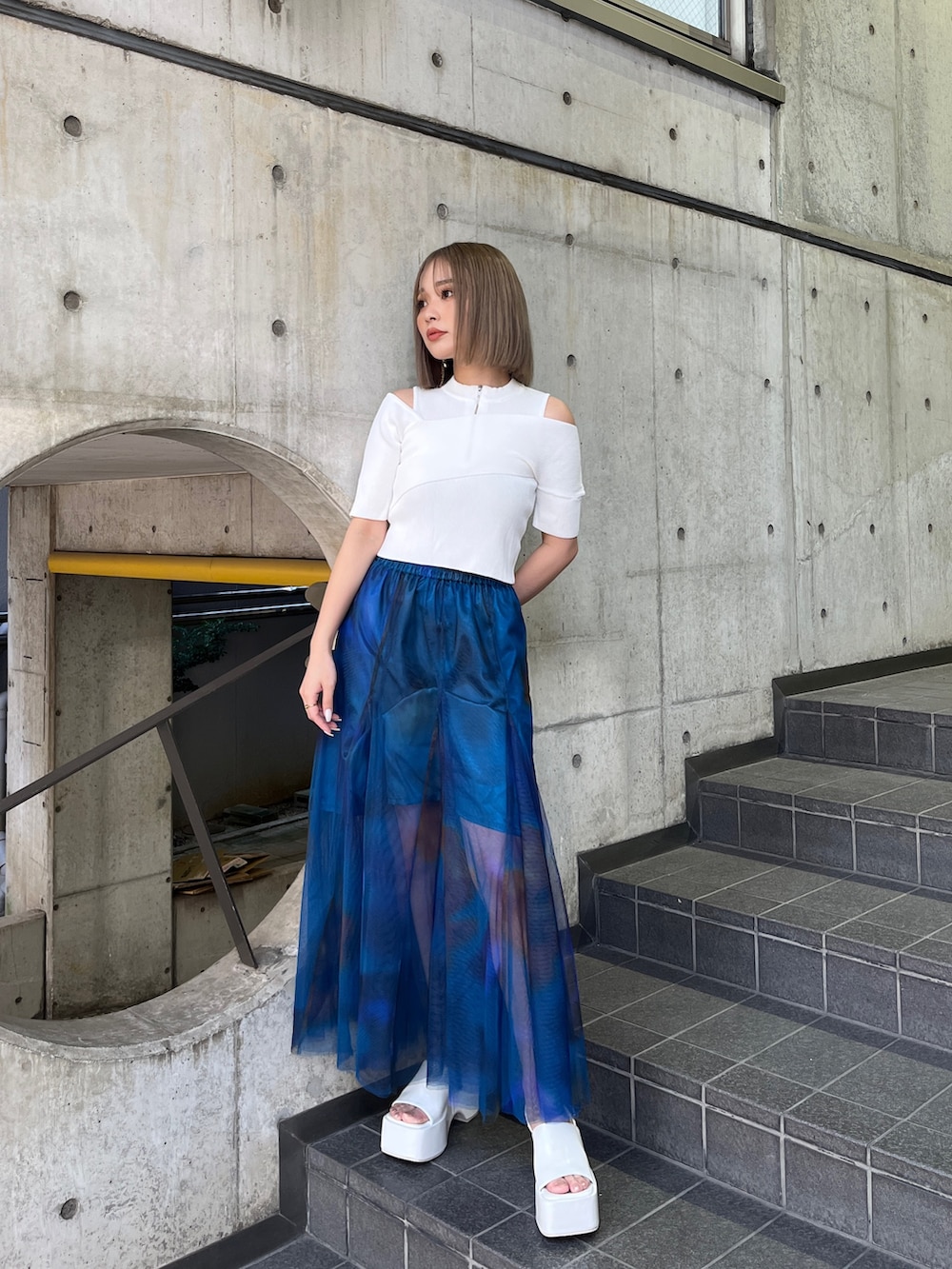 ホワイト系のニット/セーター、ブルー系のスカート、ホワイト系のサンダルを着用したレディースの冬コーディネートの2枚目の写真