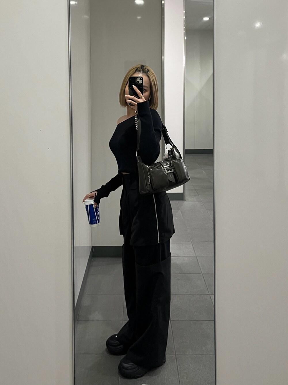 ブラック系のニット/セーター、ブラック系のスラックス、ブラウン系のハンドバッグを着用したレディースの春コーディネートの3枚目の写真