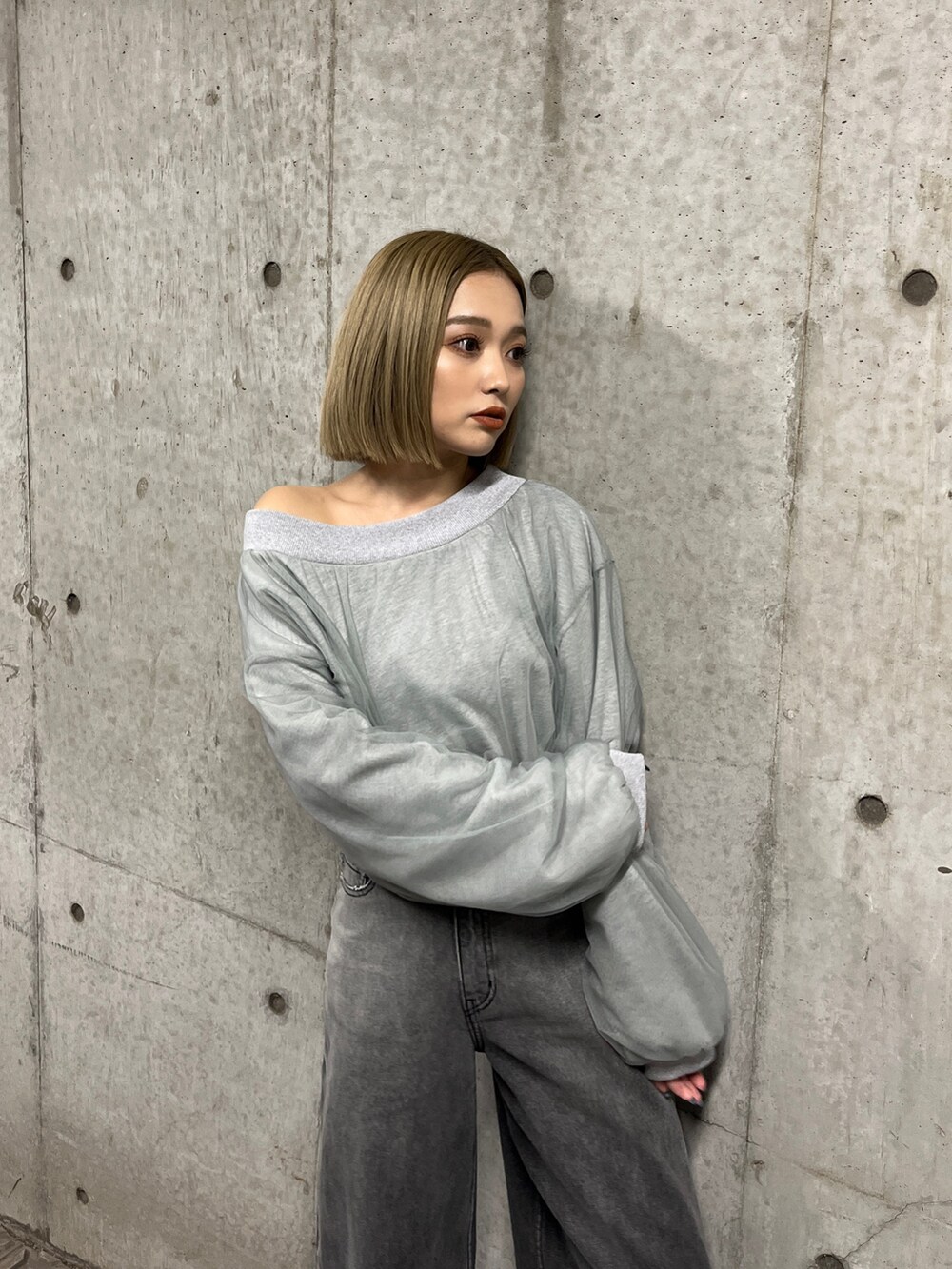 グレー系のスウェット、ブラック系のデニムパンツ、シルバー系のパンプスを着用したレディースの冬コーディネートの6枚目の写真