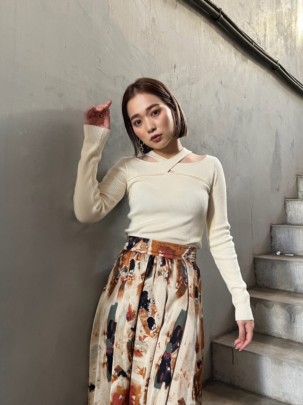 イエロー系のトレンチコート、ホワイト系のニット/セーター、オレンジ系のスカートを着用したレディースの秋コーディネートの8枚目の写真