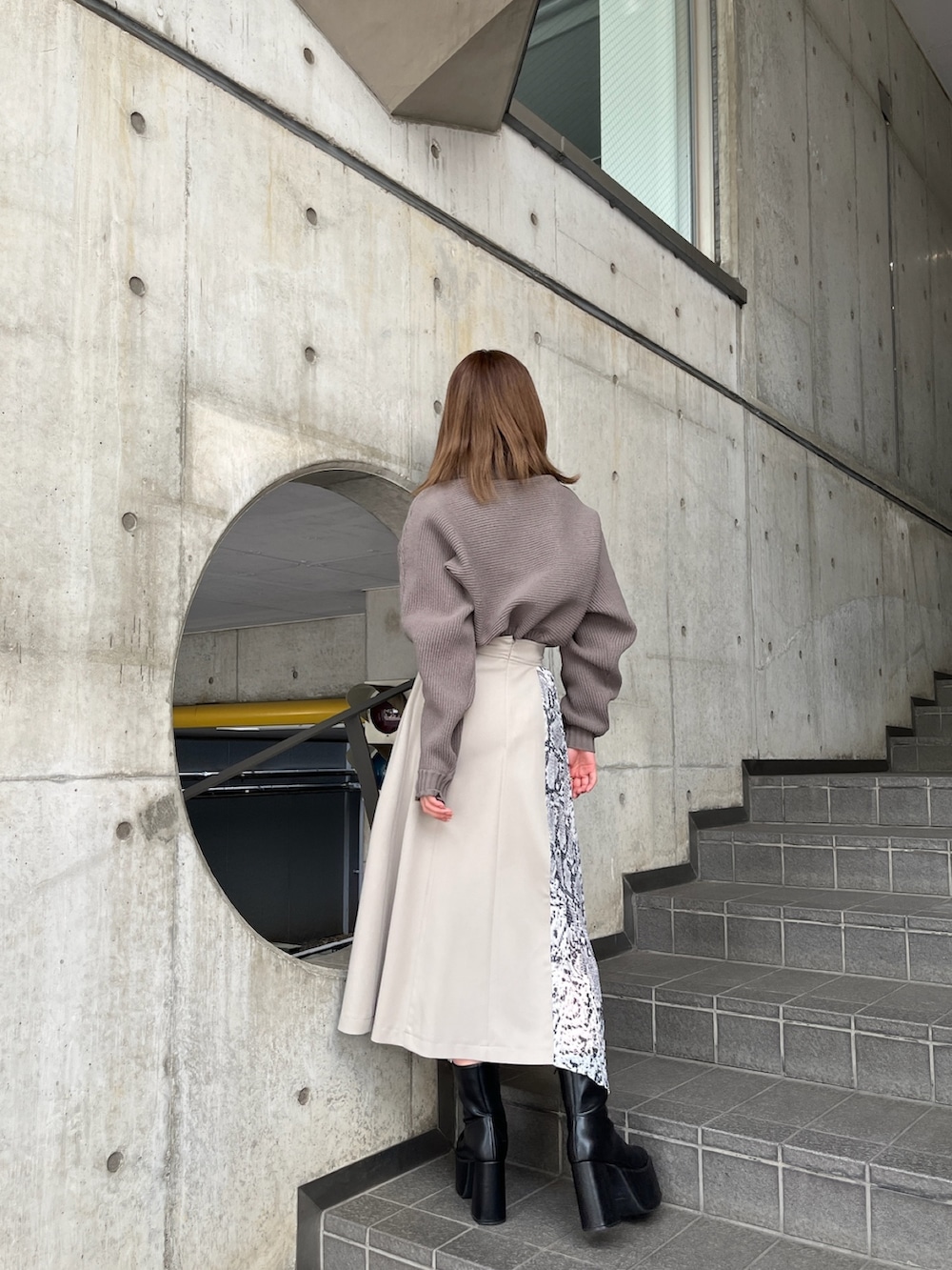 ブラウン系のニット/セーター、ホワイト系のスカート、ブラック系のブーツを着用したレディースの秋コーディネートの3枚目の写真