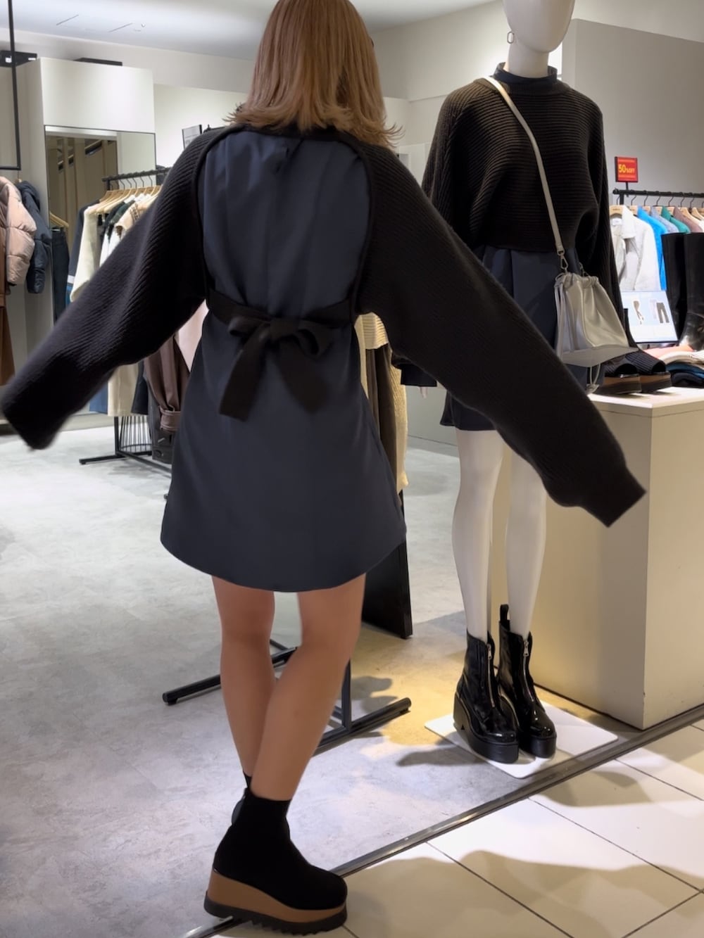 グレー系のワンピース、ブラック系のブーツを着用したレディースの冬コーディネートの2枚目の写真