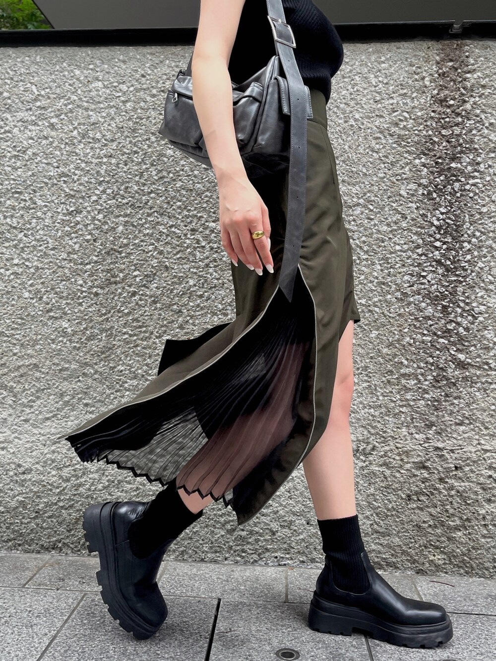 ブラック系のニット/セーター、グリーン系のスカート、グレー系のショルダーバッグを着用したレディースの夏コーディネートの6枚目の写真