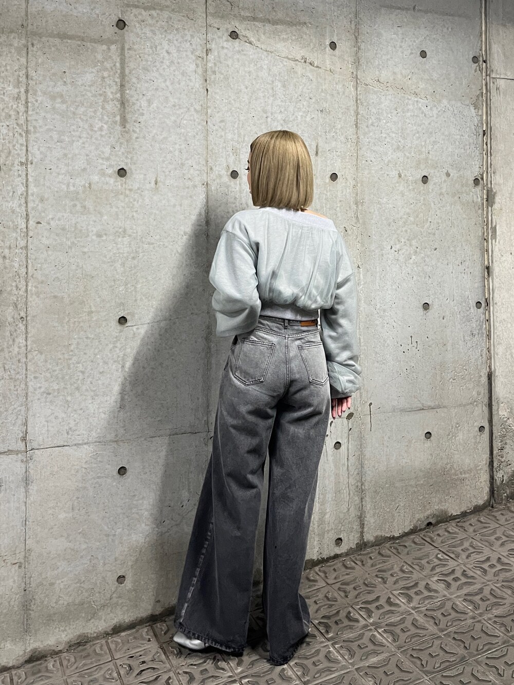 グレー系のスウェット、ブラック系のデニムパンツ、シルバー系のパンプスを着用したレディースの冬コーディネートの4枚目の写真