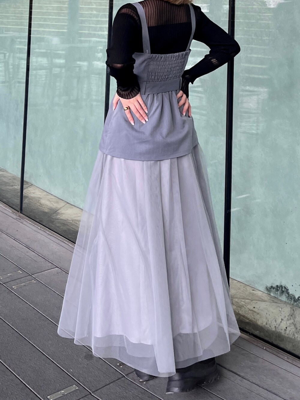 ブラック系のニット/セーター、グレー系のジャンパースカート、ブラック系のブーツを着用したレディースの春コーディネートの6枚目の写真