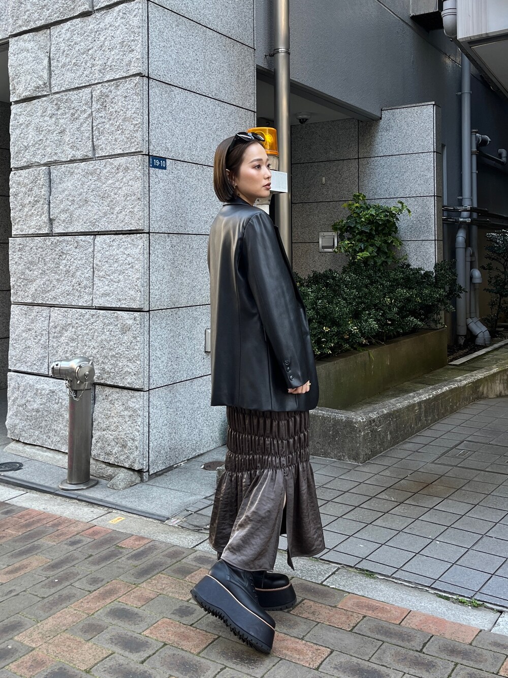 ブラック系のテーラードジャケット、ブラック系のニット/セーター、ブラウン系のスカートを着用したレディースの春コーディネートの3枚目の写真