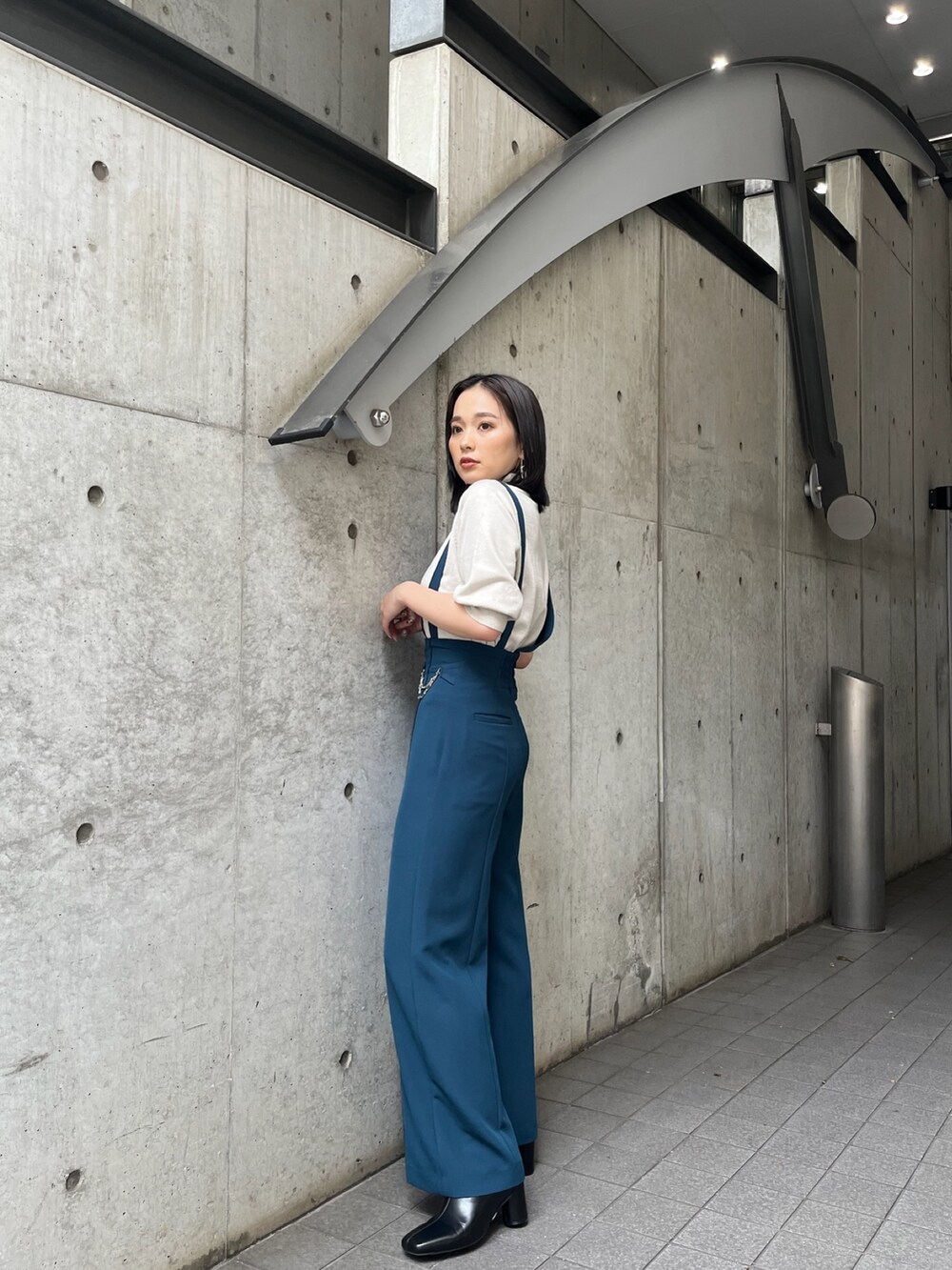 ブルー系のスラックス、ブラック系のブーツを着用したレディースの夏コーディネートの2枚目の写真